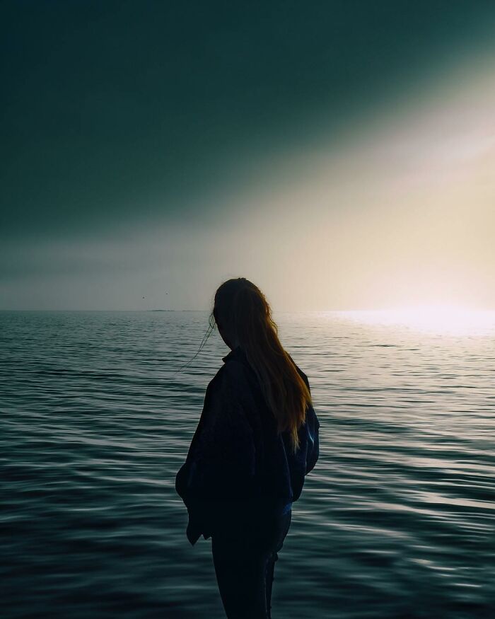 Silhouette of a person standing by the sea at sunset in a creative photo edit that questions reality.