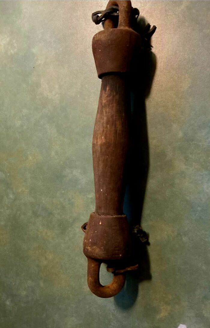 Rusty metal and worn wooden object with chains, a strange thing found in homes with hidden or haunted pasts