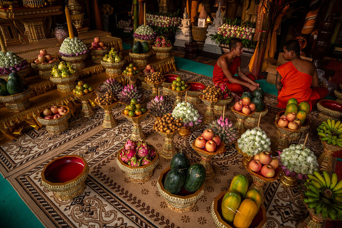 Monks with ornate baskets of vibrant fruit and flowers in a ceremonial setting, showcasing stunning food photography.