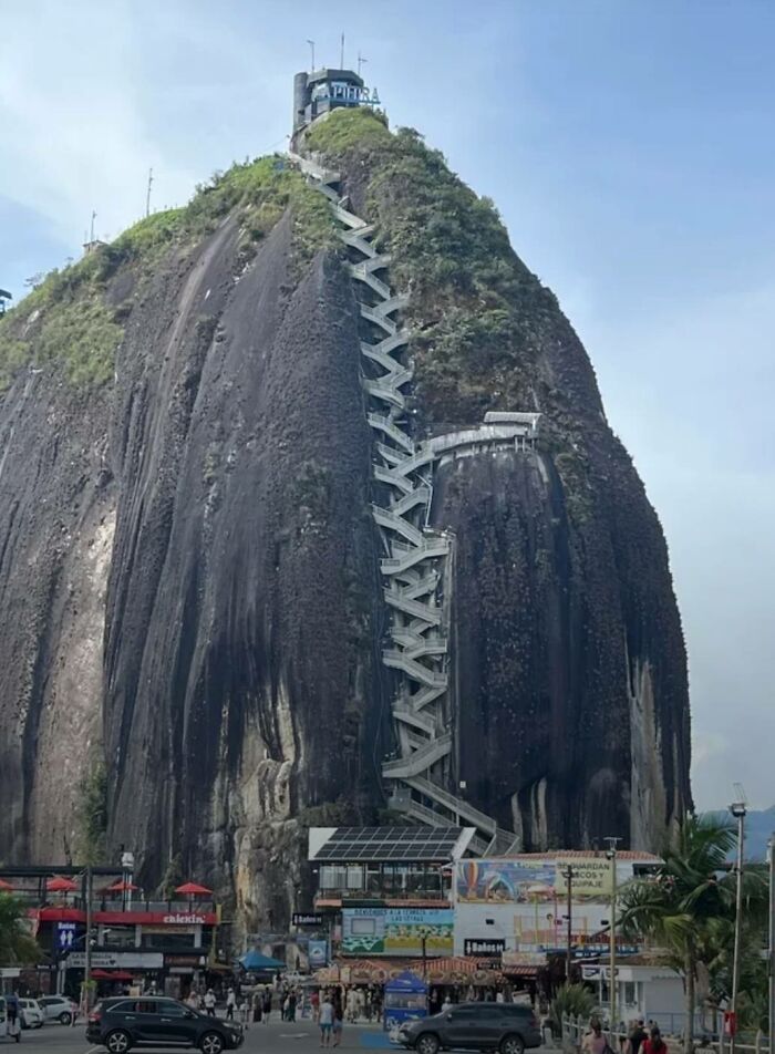 Large rock with zigzagging stairs and visitors at base, an odd find on Google Earth attracting attention.