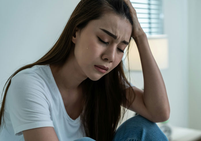 Young woman looking distressed and tearful, reflecting on secrets a spouse might keep after marriage.