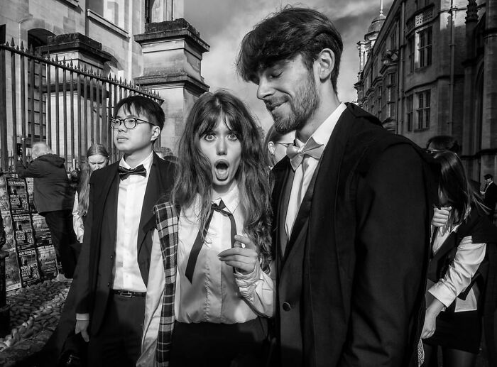 Black and white street photo of stylish young people in formal wear captured on a bustling urban street scene.