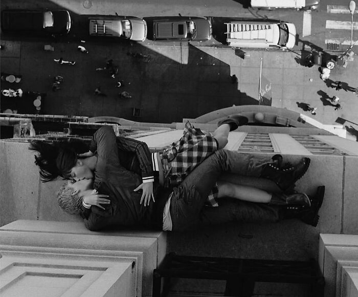 Couple kissing on ledge in a black and white street photo, part of a popular Instagram street photography collection.