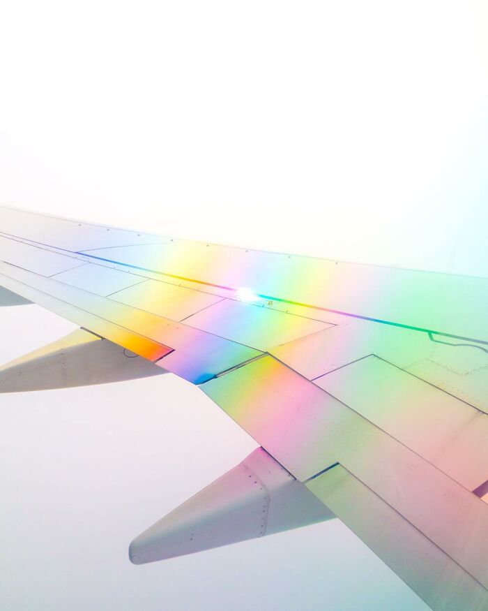 Airplane wing displaying a colorful rainbow reflection, showcasing creative photo edits that make you question reality.