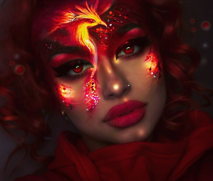 Creative makeup look featuring a fiery phoenix design with vibrant reds and detailed face art by talented artists.