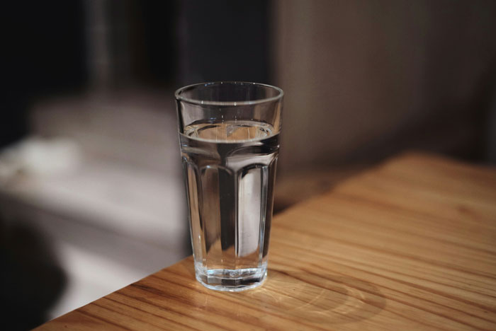 Clear glass of water on wooden table in a dimly lit room, illustrating moments when bosses or teachers went off the rails.
