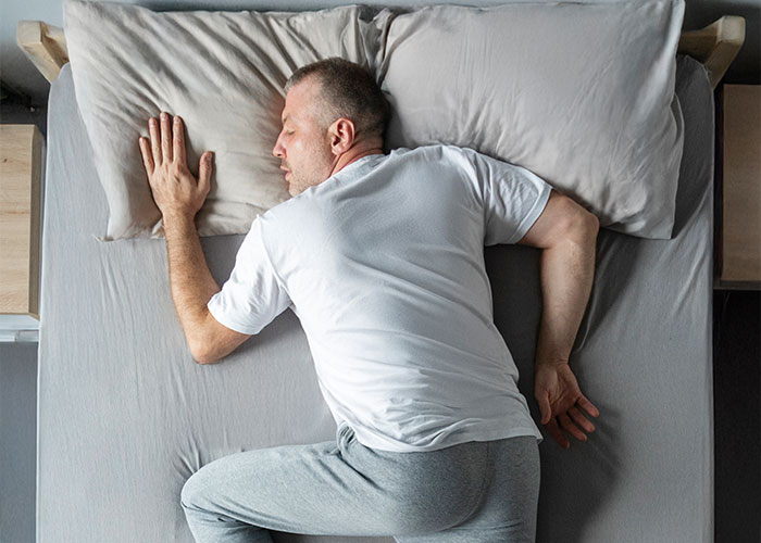 Man sleeping in bed in comfortable pajamas showing things everyone does but doesn’t talk about everyday habits