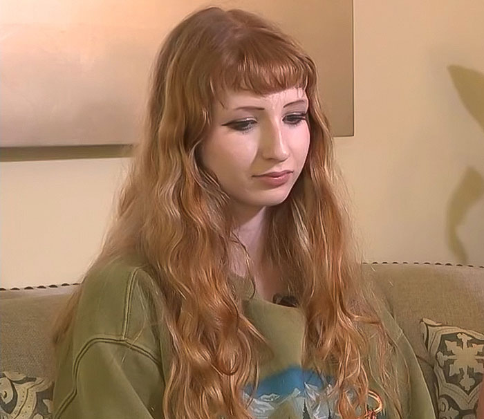 Teen girl with long red hair and green shirt sitting on a couch, involved in a debate over her trans prom date.