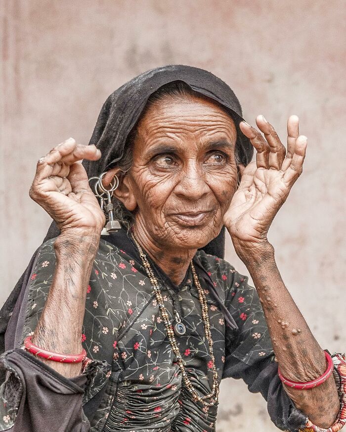 Elderly woman with large earrings and traditional attire captured in striking portrait of elderly people across the globe.