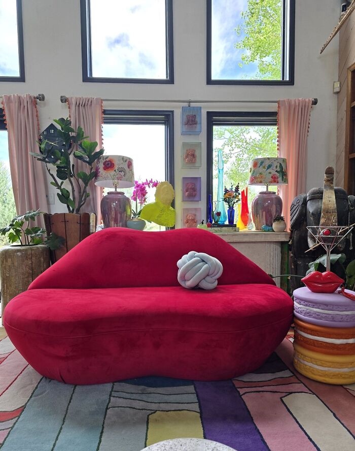 Red lips-shaped sofa in an eclectic living room with colorful decor showcasing thrifted finds collection.