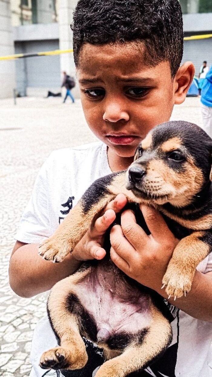 Young boy holding a puppy, capturing a heartfelt moment from the lives of homeless people and their dogs.