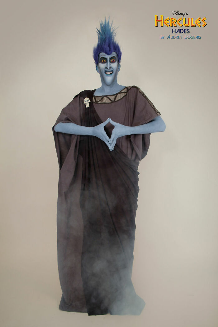 Person with blue face and hair, detailed makeup look of Hades from Disney's Hercules, wearing dark flowing robe with smoke.