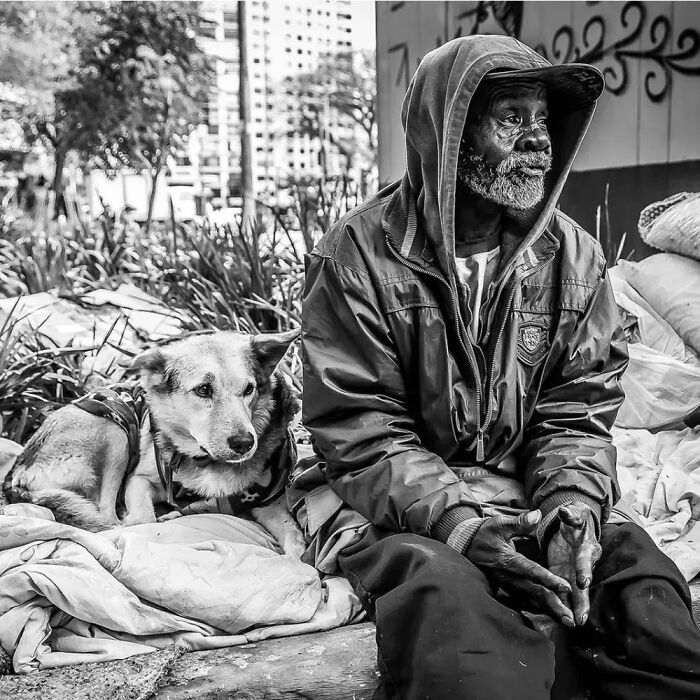 Homeless man sitting with his dog outdoors, capturing a moment from lives of homeless people and their dogs.