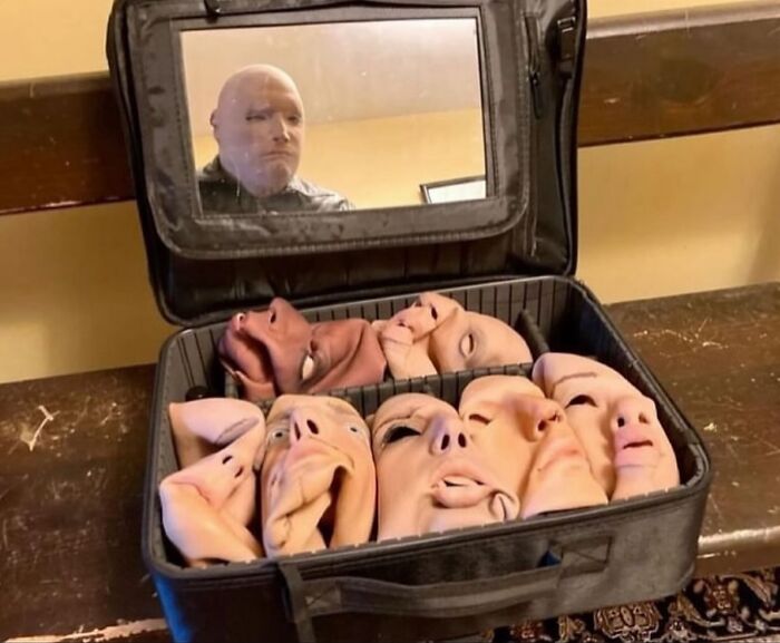 Maletín abierto con máscaras de rostros humanos deformados en una habitación, imagen maldita y perturbadora a todos los niveles.