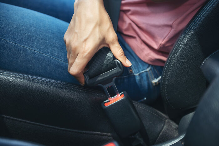 Person fastening a seatbelt in a car, highlighting casual safety habits that most people don't realize can be deadly.