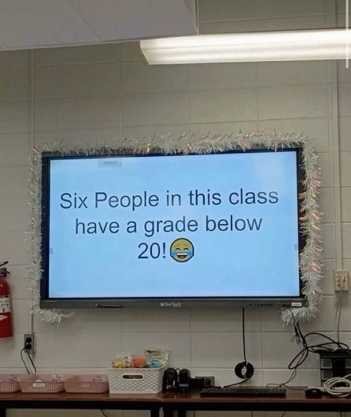 Classroom screen displaying a chaotic meme about six people having grades below 20 with a laughing emoji.