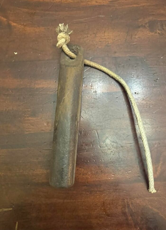 Old wooden object with rope, one of the strange things found in homes with hidden or haunted pasts, lying on a wooden surface.