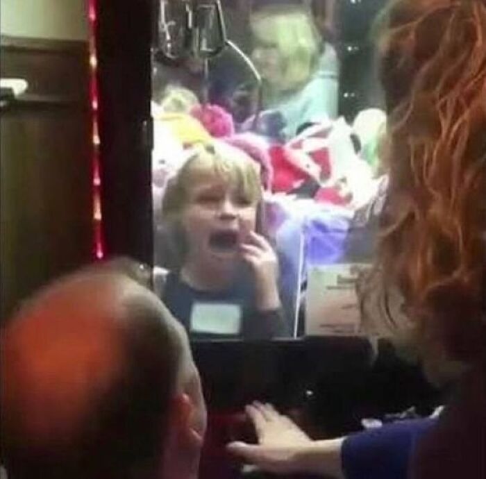 Niño atrapado dentro de máquina de gancho, imagen maldita que muestra angustia y desesperación en ambiente cerrado.