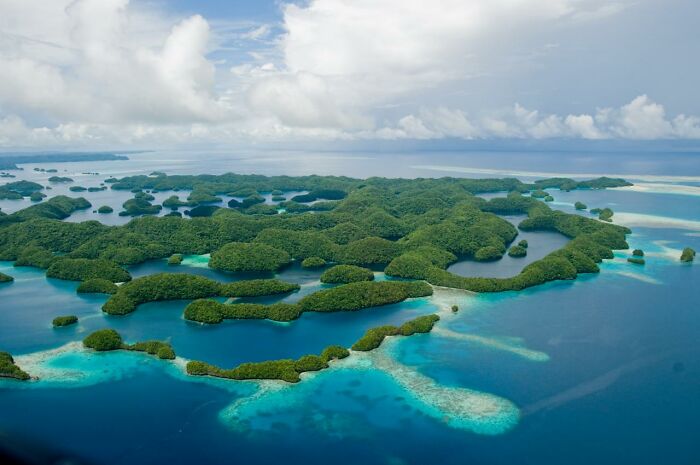 Aerial view of hidden UNESCO gems featuring lush islands and vibrant blue waters under a cloudy sky.
