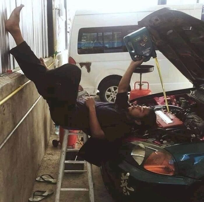Hombre reparando un auto en una posición peligrosa y poco convencional, imagen maldita capturada en un taller mecánico.