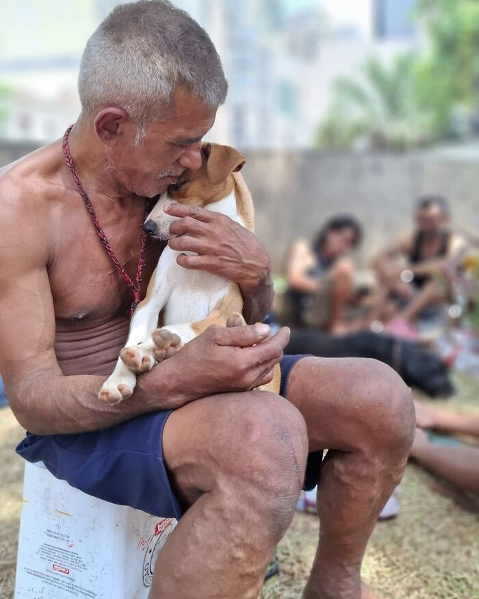 Homeless man tenderly holding and comforting his dog, illustrating the bond between homeless people and their dogs on IG page.