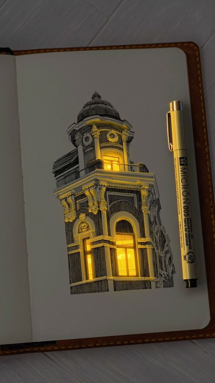 Pen and ink drawing of a glowing architectural building detail on sketchbook page with a pen beside it.