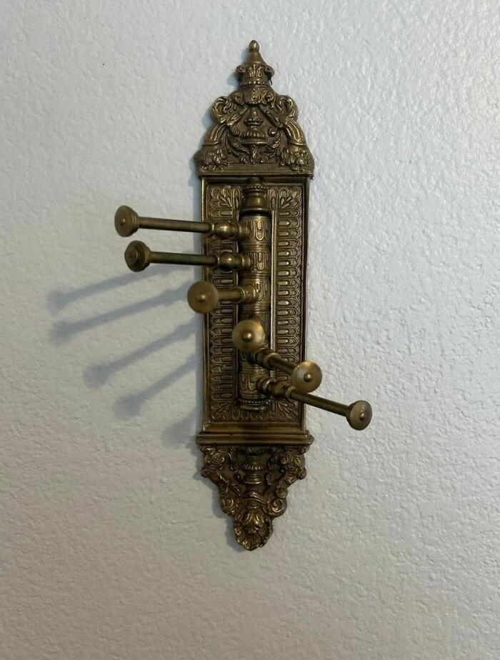 Antique brass wall mount with ornate decoration and multiple folding pegs found in homes with hidden pasts.