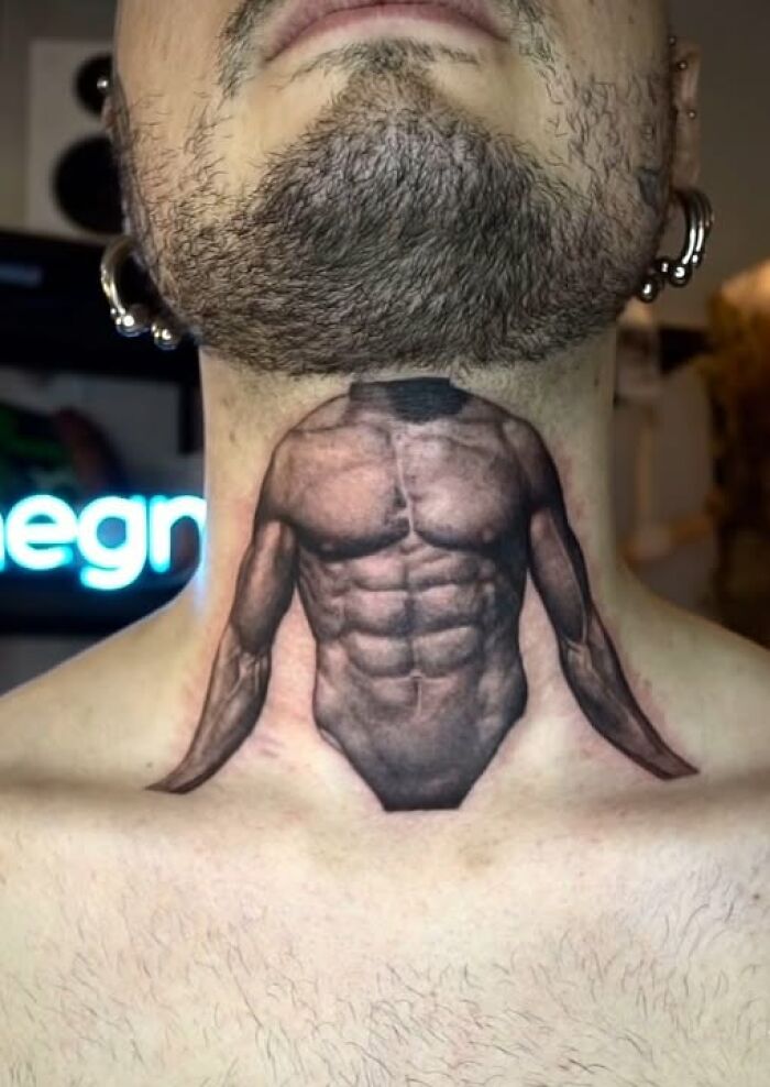 Neck tattoo of a muscular torso without a head on a man with facial hair and multiple ear piercings, showing inked mistake.