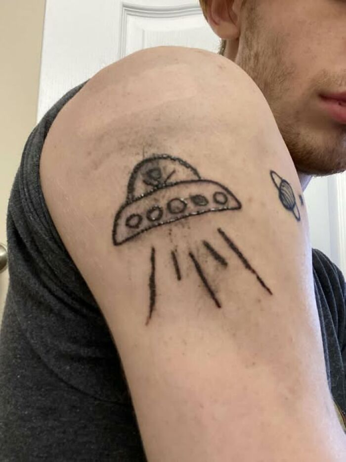 Arm tattoo of a poorly drawn UFO and planet, an example of people getting inked but ending with a permanent mistake.