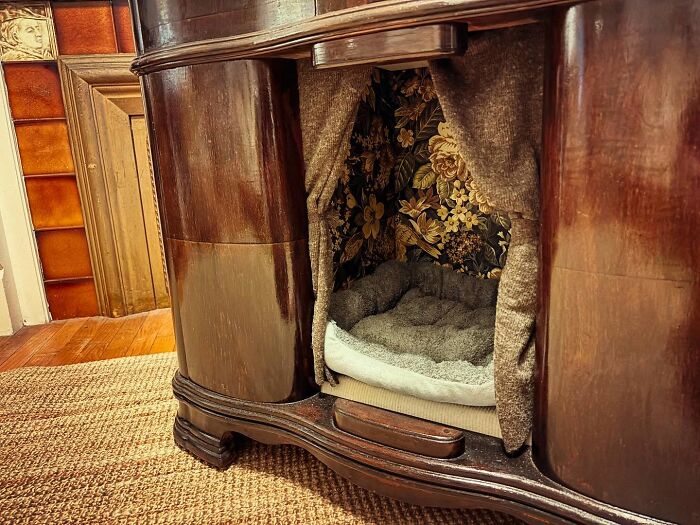 Vintage TV turned into a cozy cat bed with patterned fabric and a soft cushion inside a nostalgic nook.