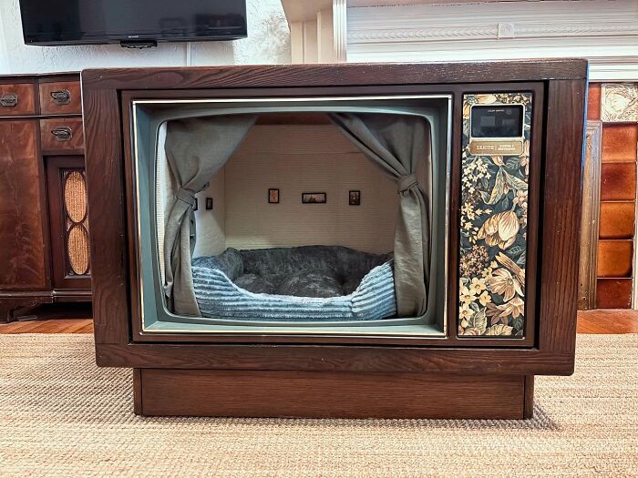 Vintage TV turned into a cozy cat bed with soft cushions and curtains, creating a nostalgic nook for pets.