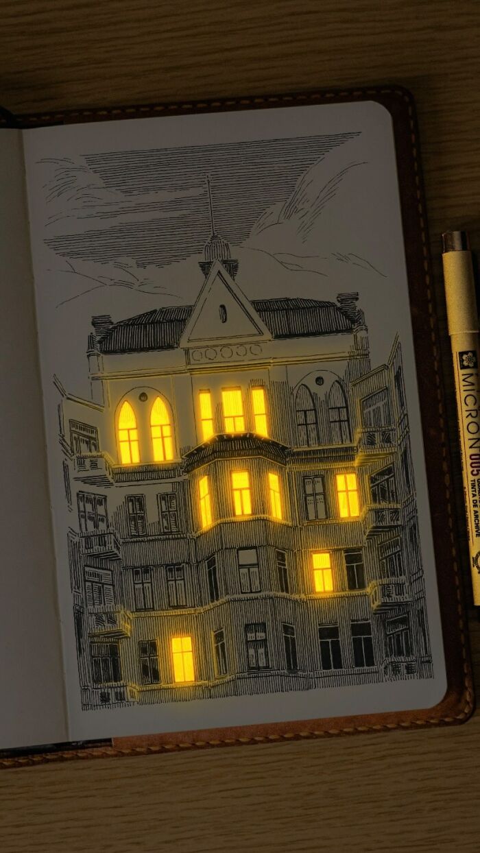 Pen and ink drawing of a building in a sketchbook with glowing light coming from the windows, showcasing Ukrainian artist’s work.