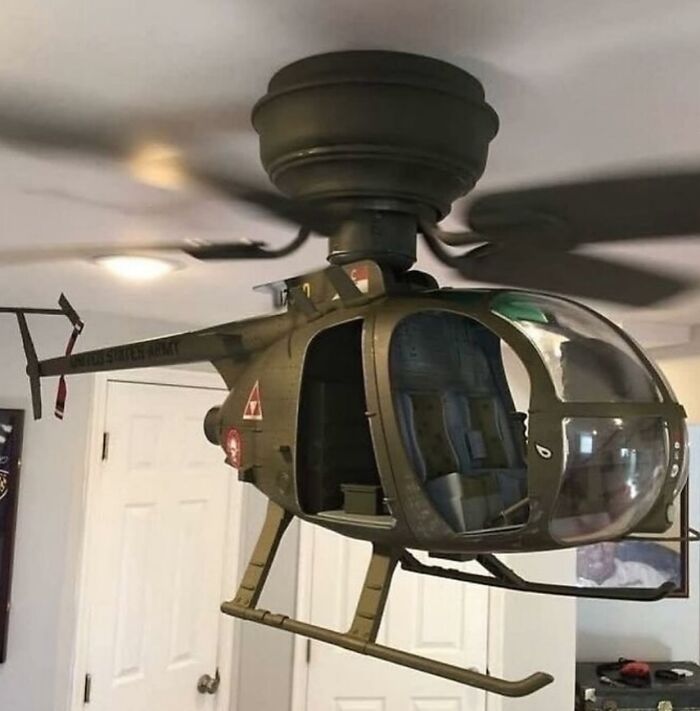 Ventilador de techo con figura de helicóptero militar en miniatura colgando dentro de una habitación.