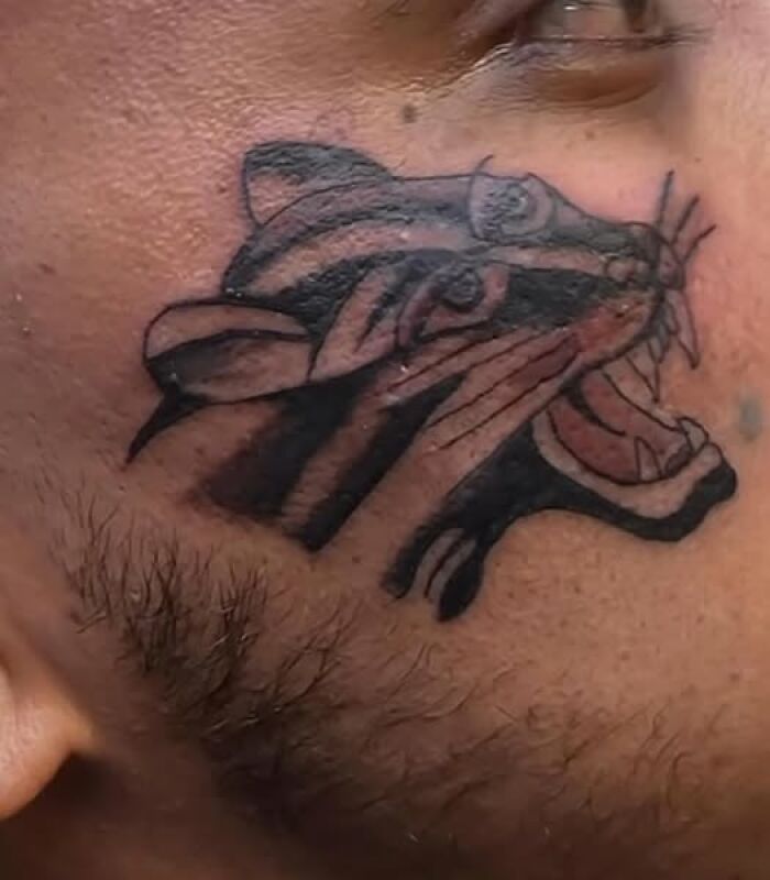 Close-up of a face tattoo showing a poorly executed tiger design, an example of people getting inked with a permanent mistake.