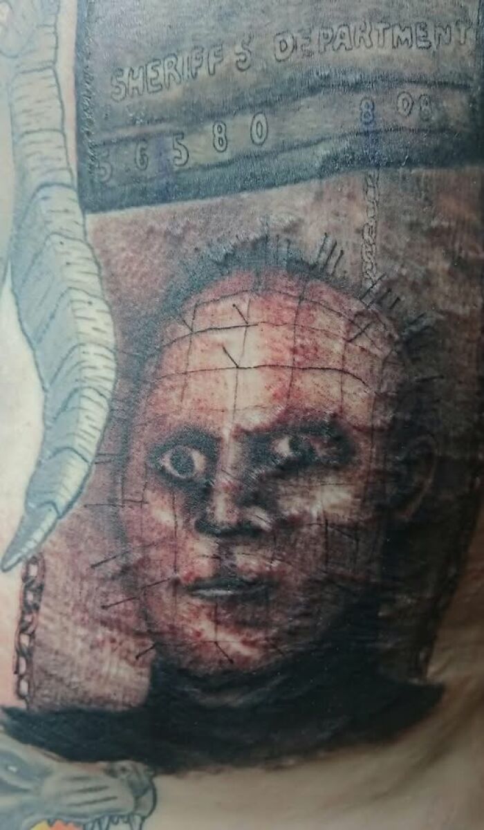 Tattoo of a distorted face with grid lines and pins, showcasing a permanent mistake in inked body art.