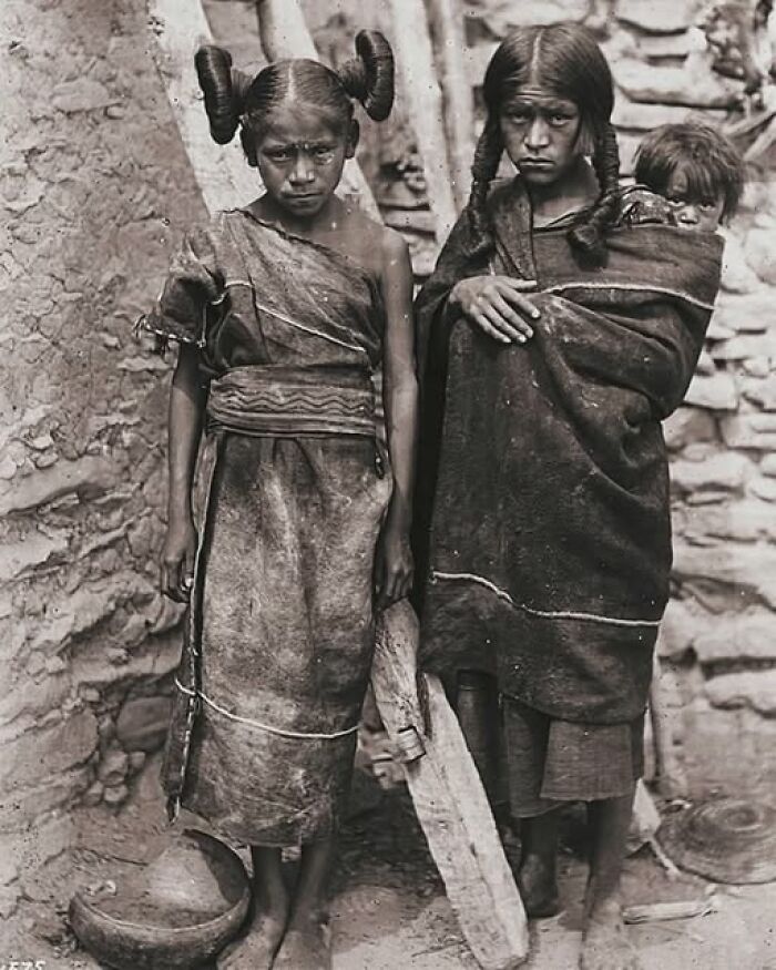 Antique historical photographs of Native American children wearing traditional clothing in a rustic stone setting.