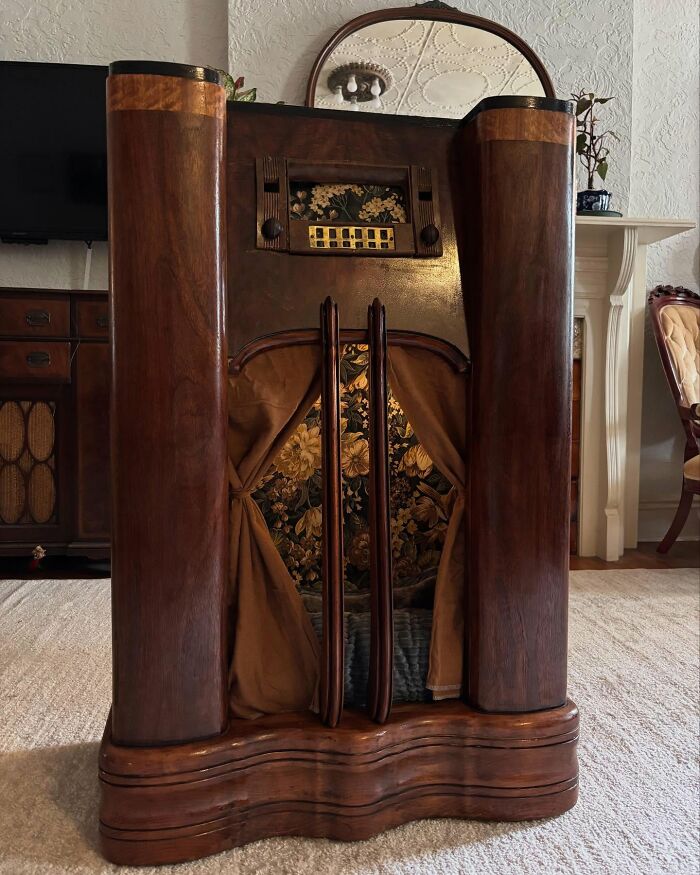 Vintage TV repurposed into a cozy cat bed with floral interior and wooden exterior in a home setting.