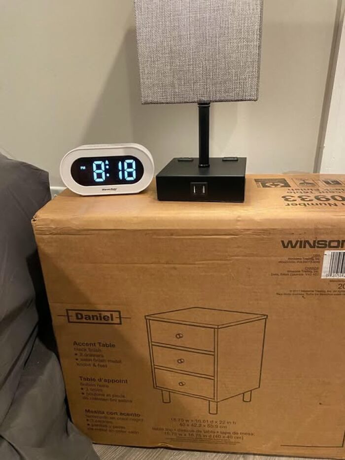 Digital clock and lamp placed on unopened cardboard box, a relatable scene for sarcastic memes about everyday life.