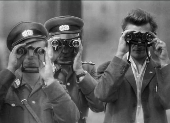 Three men in vintage attire using binoculars, a vintage historical photograph illustrating antique moments from the past.
