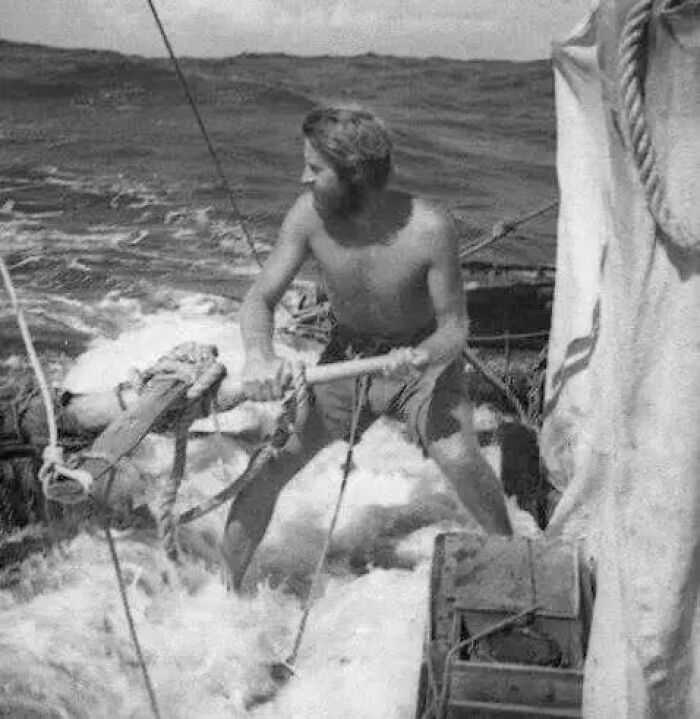 Bearded man working on a wooden sailboat in rough seas captured in an antique historical photograph.