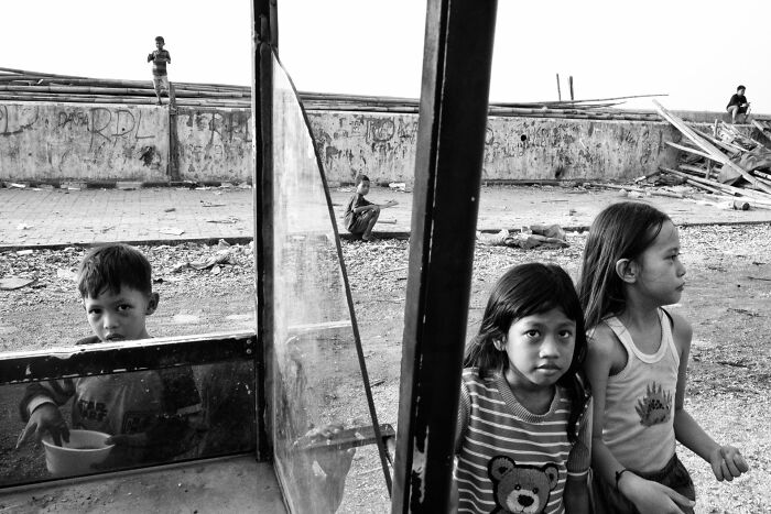 Children in a gritty urban setting captured in black and white, exemplifying pure street photography style and emotion.