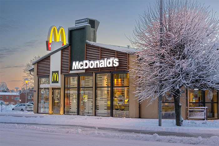 McDonald's restaurant at dusk in winter with snow-covered trees, illustrating junk food feeding scenario for nieces.