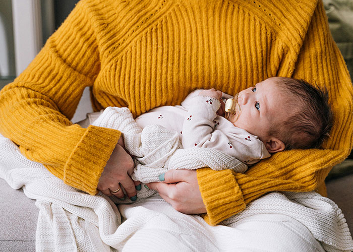 Woman holding a newborn baby wrapped in a blanket, illustrating trauma and relationship struggle with boyfriend.