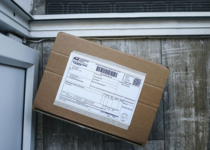 Brown cardboard package with a shipping label left on a doorstep, highlighting package theft by a neighbor incident.