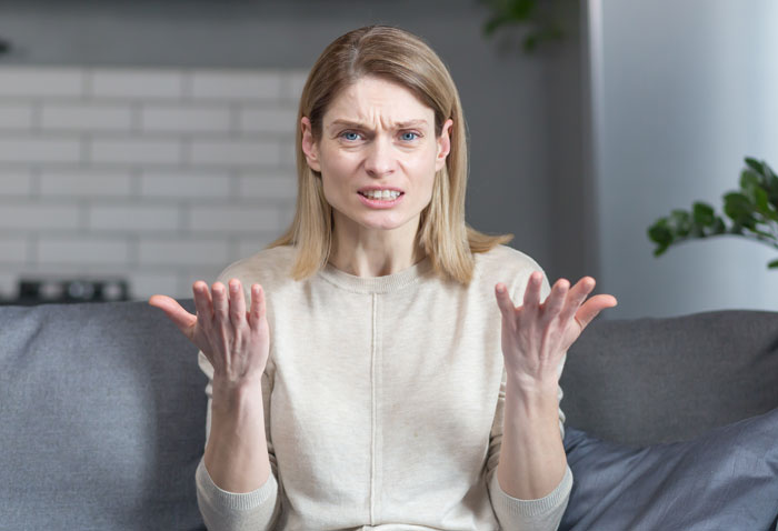 Frustrated woman sitting on couch upset after being left to babysit girlfriend&rsquo;s kids by roommate not doing parent thing