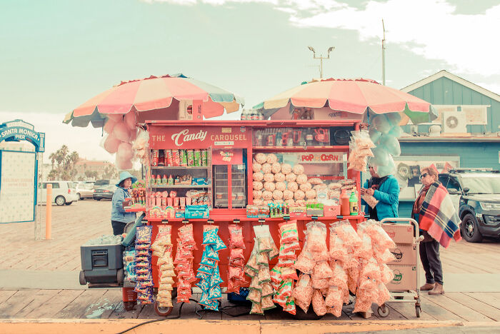 Colorful street photography moment of a candy stand with popcorn and snacks on a boardwalk by talented photographers