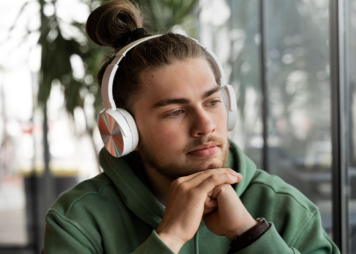Young man with headphones lost in thought, representing things everyone does but doesn’t talk about.
