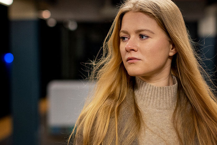 Young woman with long hair and serious expression, experiencing a scary gut feeling in an urban setting.