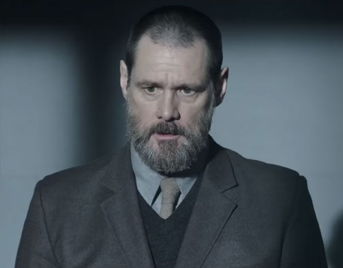 Actor with a beard in a dark suit and tie in a dimly lit setting, capturing a tense celebrity encounter moment.