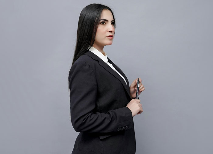 Professional woman in a black blazer holding a pen, representing bosses and authority figures in unexpected situations.